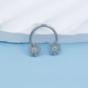 Close-up of a silver horseshoe septum ring featuring intricate spider web side designs