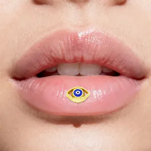 Dettaglio del piercing labiale Evil Eye dorato con smalto blu indossato da modella