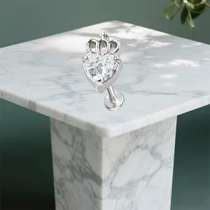 Detailaufnahme von Kronen-Herz-Piercing-Stecker mit klarem Zirkonia auf Marmor-Hintergrund