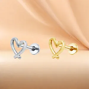Details von hohlförmigen Herz-Ohrsteckern in Gold und Silber auf rosa Seidenstoff