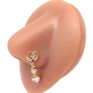 Golden heart winged nose stud with zircon dangles on a silicone nose model display