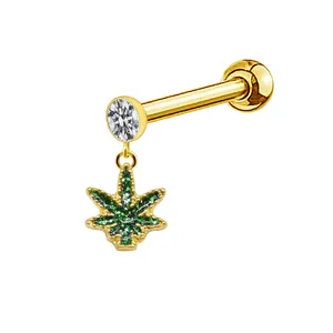 Detail of gold piercing stud featuring clear zircon and green stone cannabis leaf pendant
