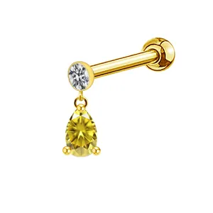 Macro detail of gold piercing stud featuring a white zircon and yellow teardrop gem