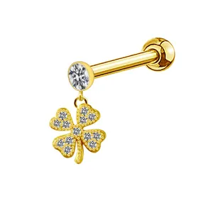 Detailed macro view of a gold piercing stud featuring a sparkling clover pendant with zircons