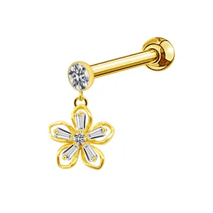 Macro shot of gold labret earring featuring a dangling openwork five-petal flower charm