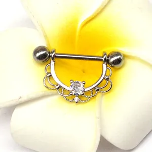 Close-up of zircon nipple ring with woven crown design placed on a white flower