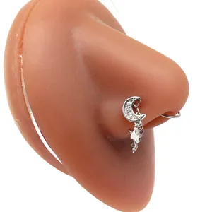 Close-up of a silver nose ring with a crescent moon and star chain on a silicone model