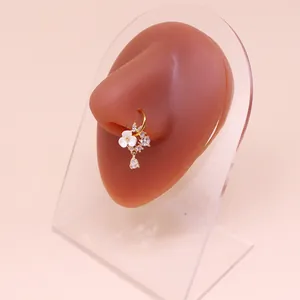 Dettaglio anello al naso dorato con fiore bianco e zircone a goccia su modello in silicone