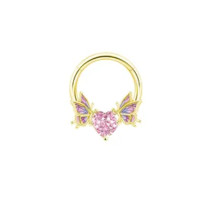 Dettaglio di gioiello per il corpo dorato con zircone rosa a cuore e ali di farfalla