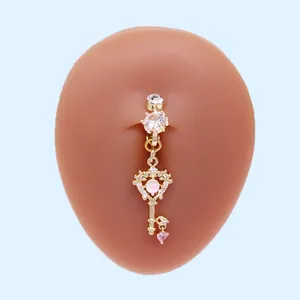 Nahaufnahme des goldenen Bauchnabelpiercings mit Herzschlüssel-Anhänger und rosa Steinen