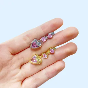 Detail von gold- und silbernen Herz-Bauchnabelpiercings mit rosa Kristallen