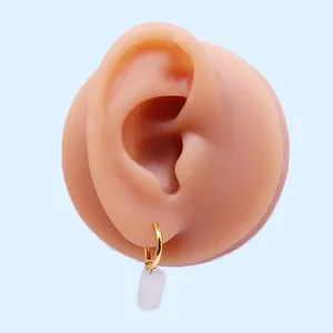 Dettaglio dell'orecchino a cerchio dorato con pendente bianco traslucido indossato