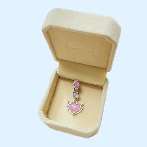 Makroaufnahme von Silber-Bauchnabelpiercing mit rosa Herz-Edelstein in einer Box