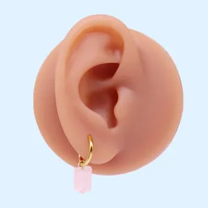 Dettaglio dell'orecchino pendente rosa traslucido con cerchio dorato su modello