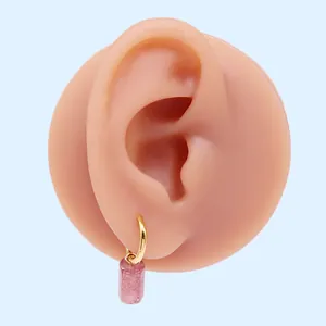 Dettaglio di un orecchino d'oro con una pietra rosa cilindrica su un espositore