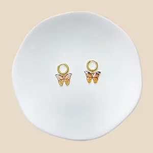 Detailaufnahme von goldenen Schmetterlings-Ohrringen mit orange-schwarzen Flügeln