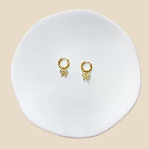 Makroaufnahme von Gold-Creolen mit Schmetterlingsanhängern und weißen Zirkonia-Steinen