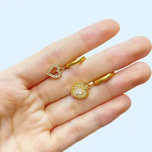 Herz-Ohrhänger in Gold mit Kristallen, präsentiert auf einem Handmodell für Damen