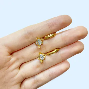 Detail goldener Creolen mit herzförmigem Zirkonia in einem planetarischen Ringdesign