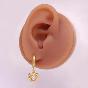 Detail eines herzförmigen Goldohrrings mit Zirkonia an einem Silikon-Ohrmodell