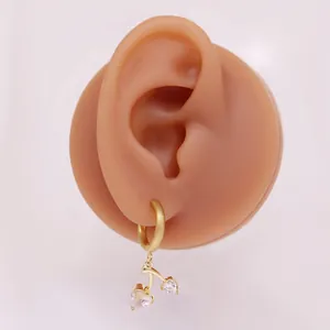 Details von goldenen Kirschohrringen mit herzförmigen Zirkonia am Modellohr