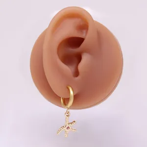 Detail von goldenem Seestern-Ohrring mit rosa Zirkon auf Silikon-Ohrmodell