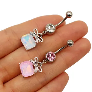 Detail of heart bow navel rings with pink and opal rectangle gems in hand