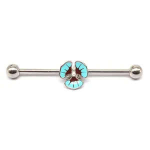 Macro detail of industrial barbell earring with blue floral charm and steel balls