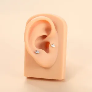 Detailed view of titanium leaf-shaped stud earrings with marquise crystals on ear model