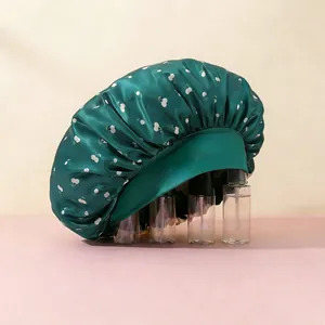 Detalle del gorro de dormir de satén verde oscuro con estampado de cerezas y banda ancha