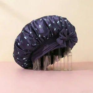 Detail of purple satin sleep bonnet featuring white cherry prints and a large silk bow decoration