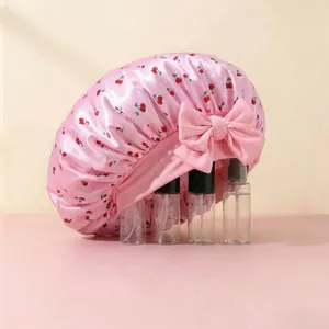 Detail of pink satin sleep cap with cherry print and large decorative bow on the side