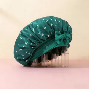 Detailed close-up of dark green satin sleep cap with cherry print and side bow detail