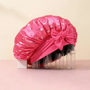 Detail of pink satin sleep cap with cherry print and large decorative side bow