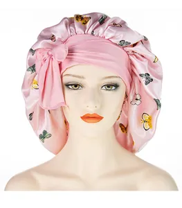 Detailansicht der rosa Satin-Schlafmütze mit Schmetterlingsdrucken und großer Zierschleife