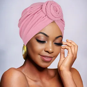 Detail of pink knitted turban hat featuring a decorative floral knot and elegant texture