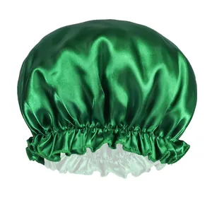 Close-up of emerald green satin sleep cap with ruffled elastic band and smooth texture