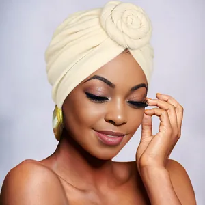Close-up of beige turban hat featuring a twisted floral design in soft knit fabric