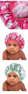 Detail of baby satin bonnets with unicorn patterns and elastic headbands in pink and green