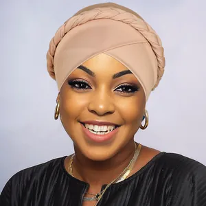 Detail of nude pink turban hat featuring a thick braided design and cross front style
