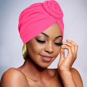 Detailed view of pink pleated turban hat featuring a decorative spiral top knot design