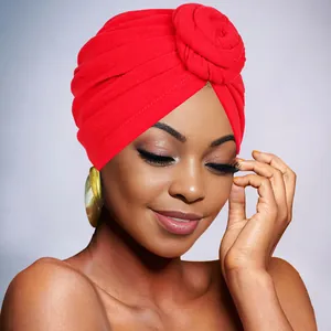 Detail of red turban hat with flower knot and large golden round earrings for women