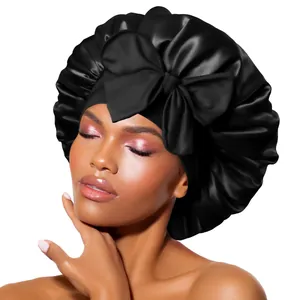 Détail du bonnet de nuit en satin noir avec un grand nœud décoratif et bande élastique