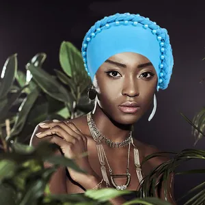 Dettaglio di un turbante blu acceso con bordo intrecciato e eleganti perle applicate