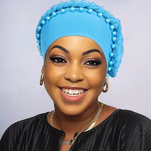 Dettaglio del turbante azzurro con parte superiore intrecciata e perline abbinate