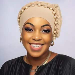 Dettaglio del design a treccia e perle bianche sul turbante beige da donna