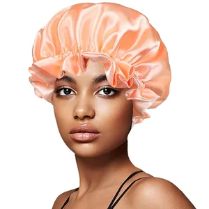 Close-up of coral satin hair bonnet featuring elastic wide band and ruffled edge details