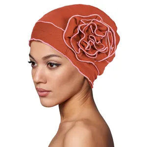 Detail of soft turban cap with large handmade layered flower and pink stitched edges