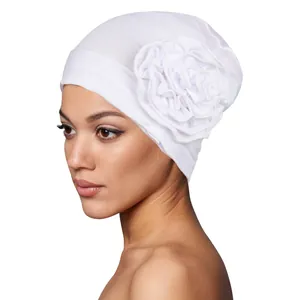 Detailed side view of a white turban hat with a large 3D fabric flower on soft knit fabric