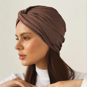 Close-up of side profile showing dark coffee twisted knot turban hat in stretch fabric